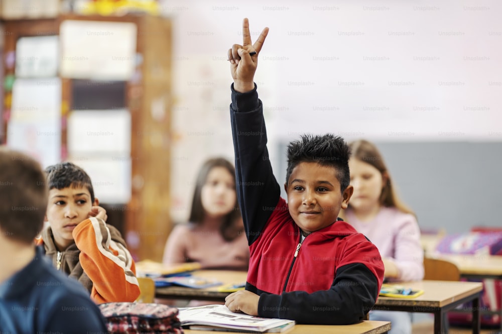 学校で手を挙げて質問に答えるインドの子供。