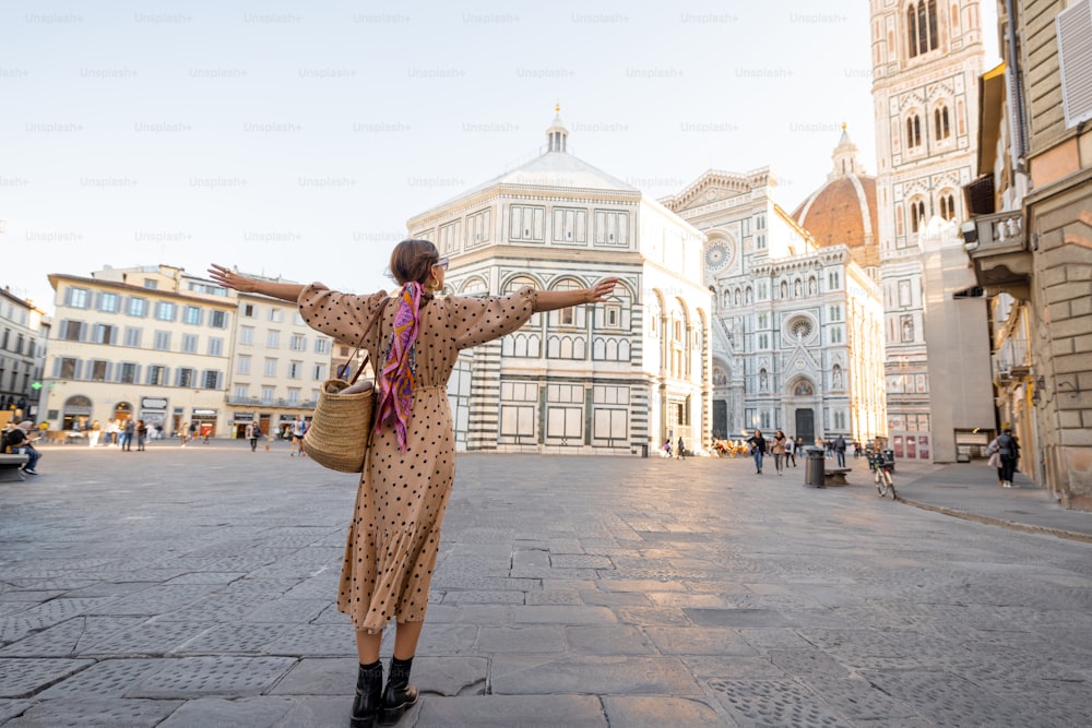 A mulher desfruta de uma bela vista sobre a famosa catedral Duomo em Florença, de pé na praça da catedral vazia durante a manhã. Mulher elegante visitando marcos italianos. Conceito de viagem pela Itália