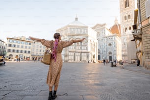 Woman enjoys beautiful view on famous Duomo cathedral in Florence, standing on empty cathedral square during morning time. Stylish woman visiting italian landmarks. Traveling Italy concept