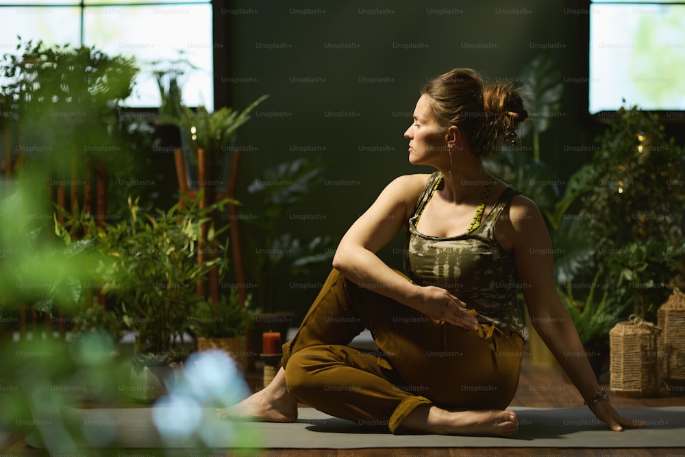 modern 40 years old woman with yoga mat stretching in the modern green house.