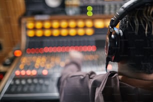 プロのレコーディングスタジオのオーディオワークステーションでヘッドフォンを装着した若いミュージシャンの背面図、コピー用スペース
