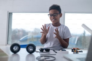 Leisure. A cute teen sitting at the table and playing with toy wheels