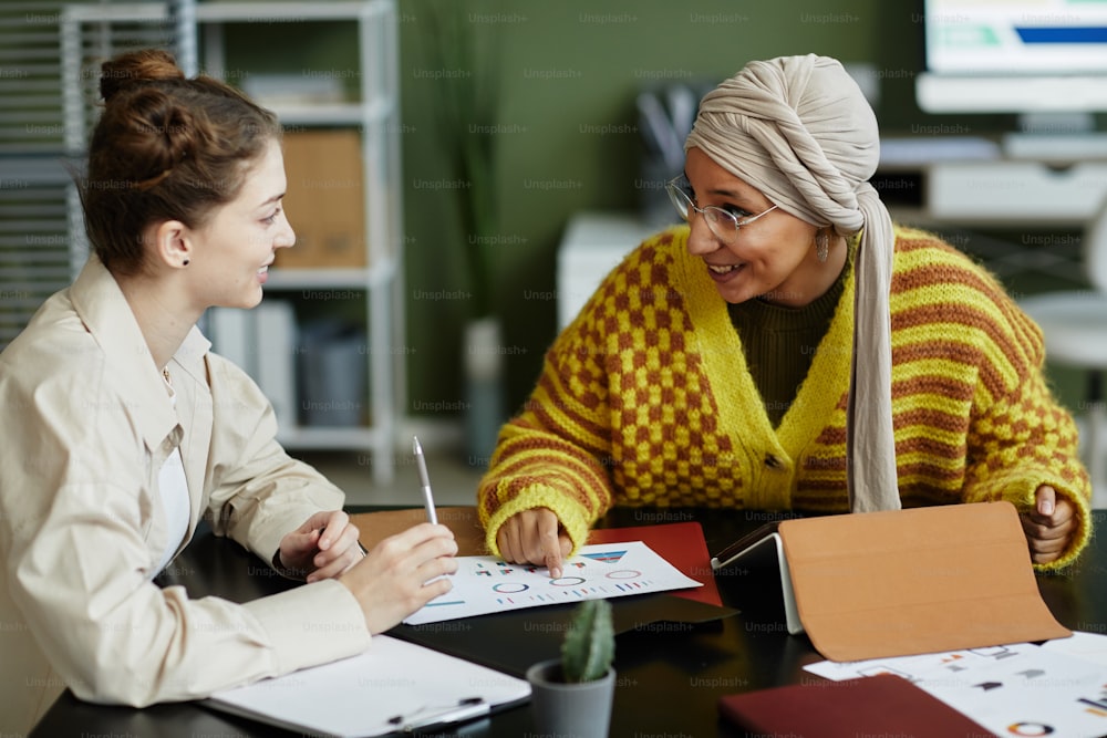 Portrait of two creative young women collaborating in business meeting while enjoying work on project together