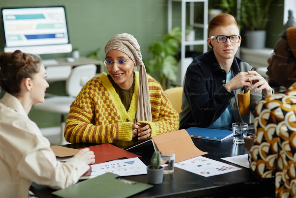 Portrait of creative young woman with team working on project together in business meeting