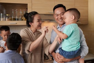 Happy Vietnamese family with three children standing together in kitchen