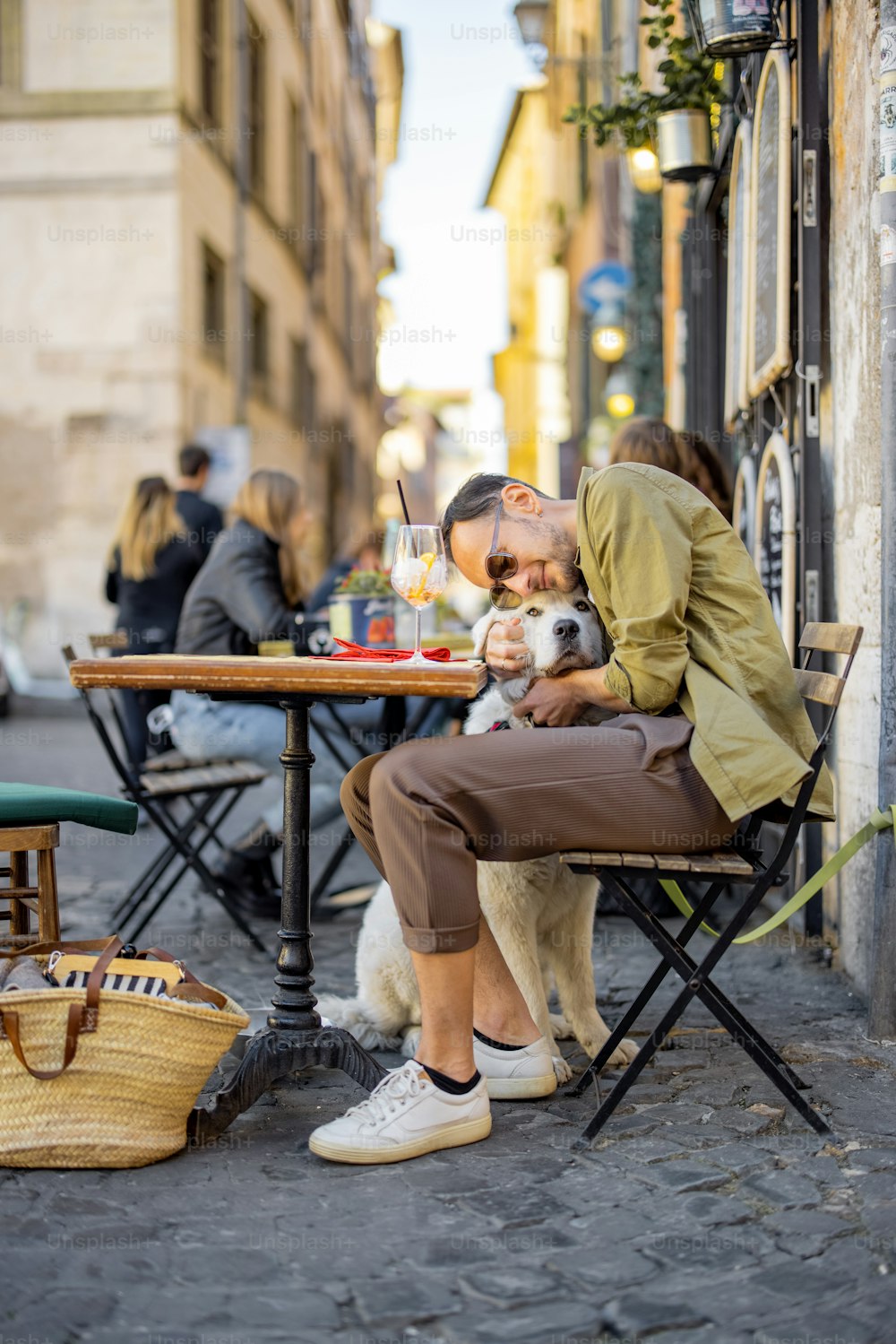 ローマの路上のレストランで犬と一緒に座っている男性。イタリアのライフスタイルのコンセプト。犬との友情のアイデア