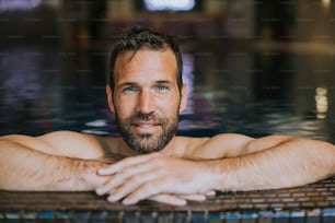 Portrait of handsome smiling young man relaxing by the swimming pool edge