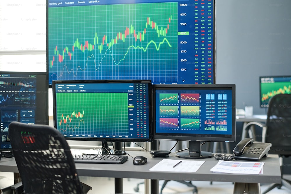 Horizontal no people shot of stock and currency trading agents workspace with desktop computers and various monitors in modern office interior