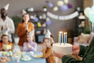 Primer plano del padre cargando pastel con velas quemadas para felicitar a su hijo con el cumpleaños