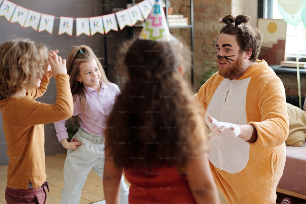 Artista masculino disfrazado de animal con maquillaje en la cara jugando con un grupo de niños en la fiesta de cumpleaños