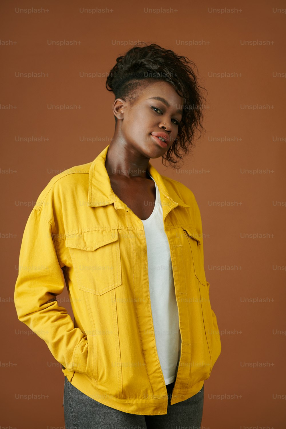 Retrato de una joven negra segura de sí misma con chaqueta amarilla de mezclilla mirando a la cámara