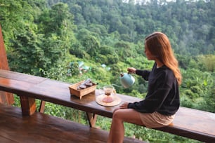 Eine junge Frau, die Filterkaffee mit einem schönen Blick auf die Berge und die Natur im Hintergrund zubereitet