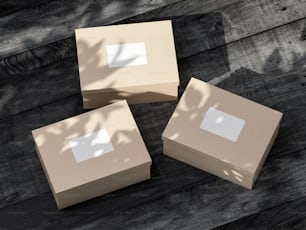 Trois boîtes en carton Maquette avec des autocollants blancs sur table en bois noir. Rendu 3D