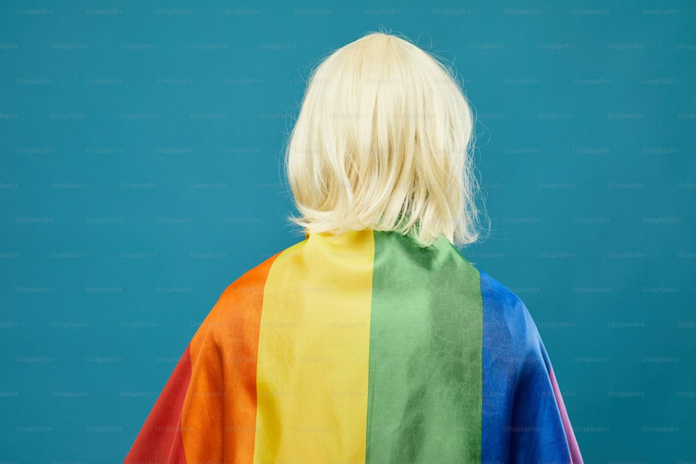 Back view of person rainbow flag against vibrant blue background LGBTQ pride