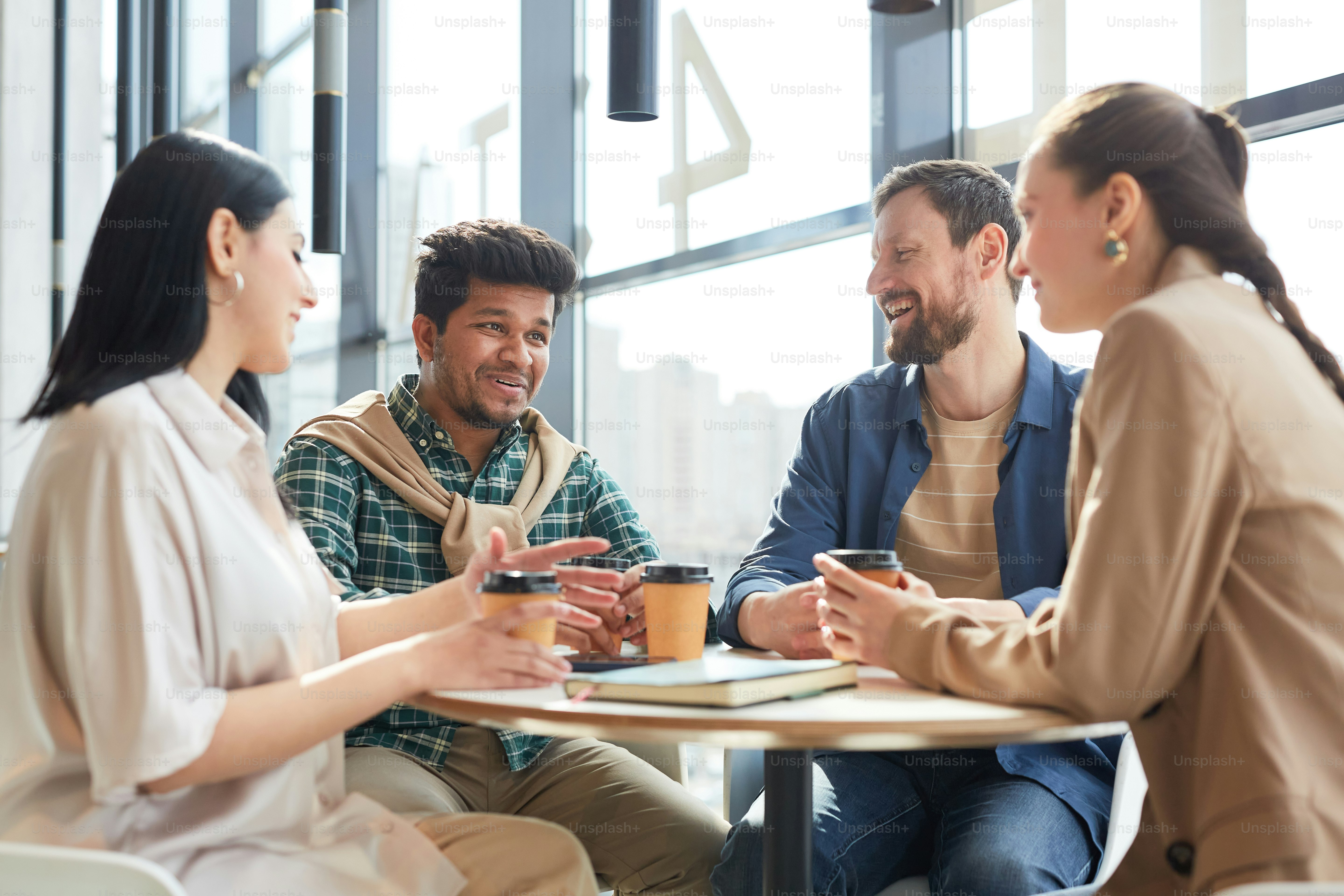 Diverse group of cheerful adult people sitting at table in food court cafe