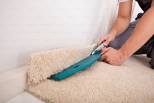 Close-up Of A Person Installing Floor Carpet With Cutter