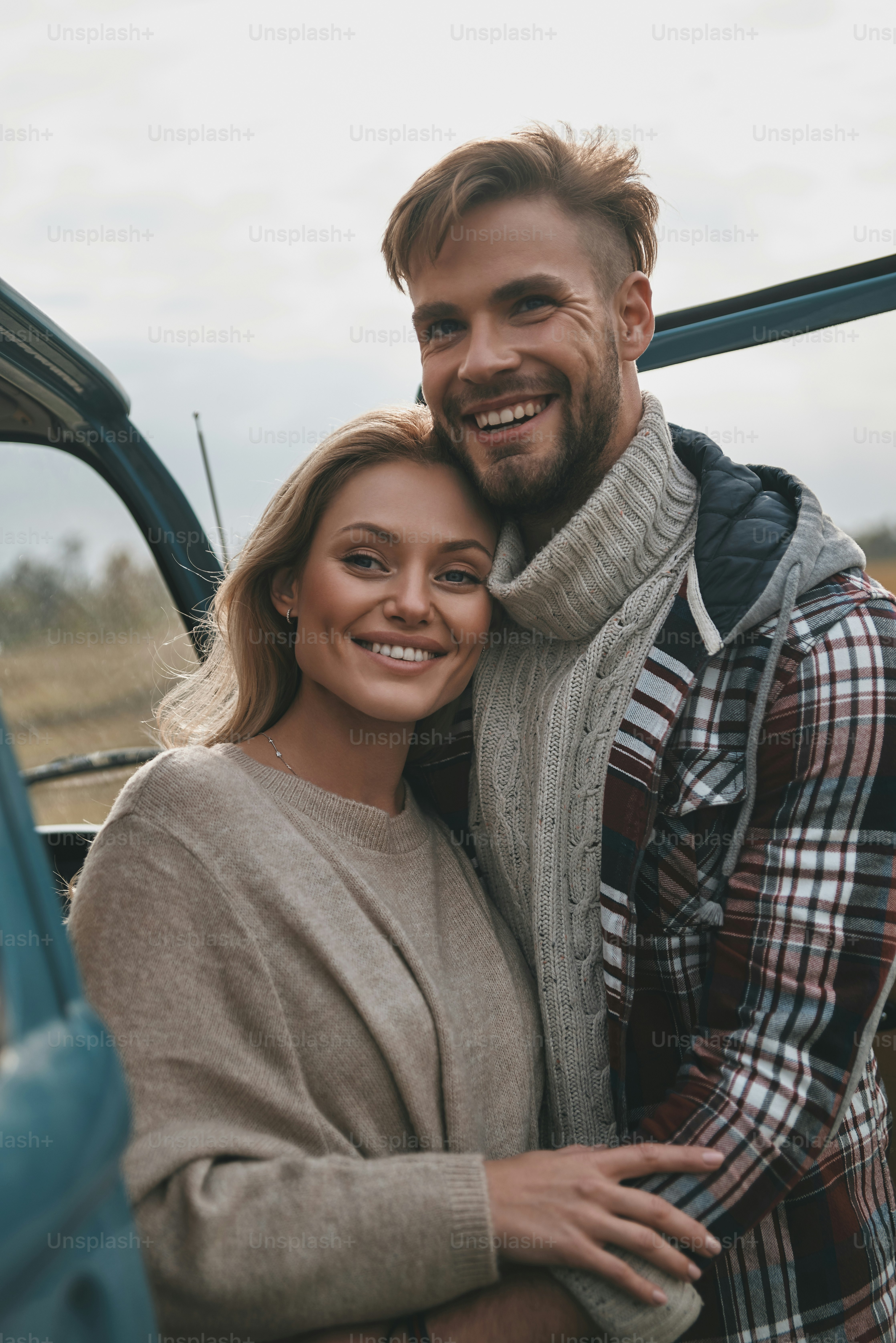 Beautiful young couple embracing and smiling while standing outdoors