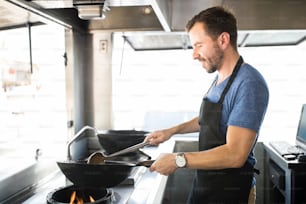 Portrait of a good looking young chef cooking some of his favorite dishes in a food truck