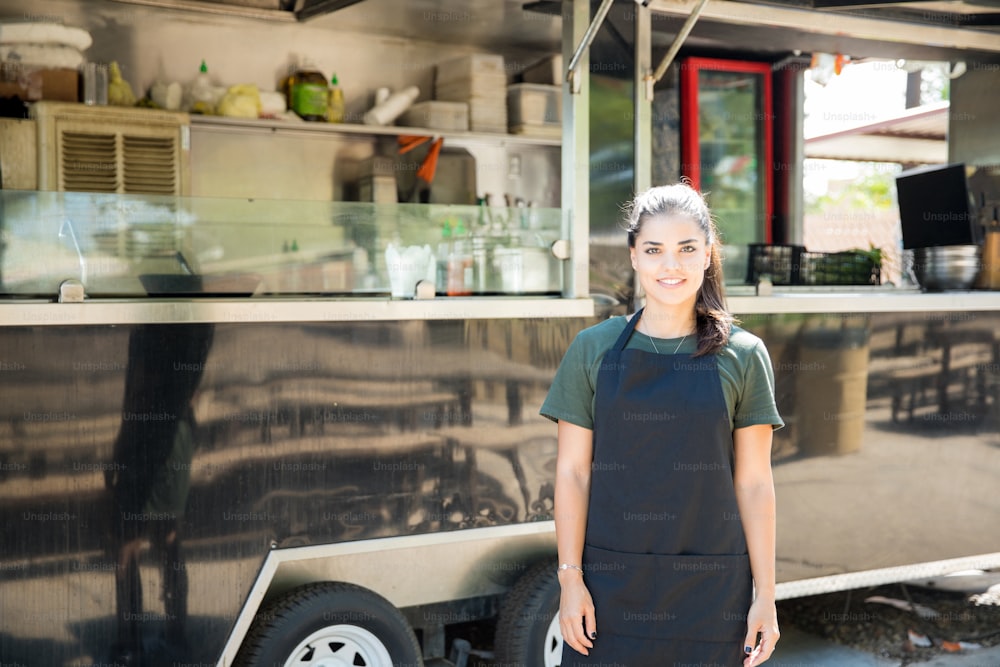 Retrato de una hermosa joven hispana propietaria de un camión de comida lista para cocinar