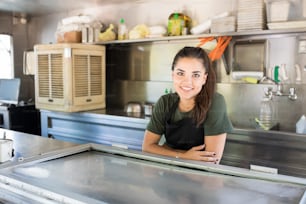 Süße junge Brünette, die an einem Imbisswagen arbeitet und ihren Job genießt