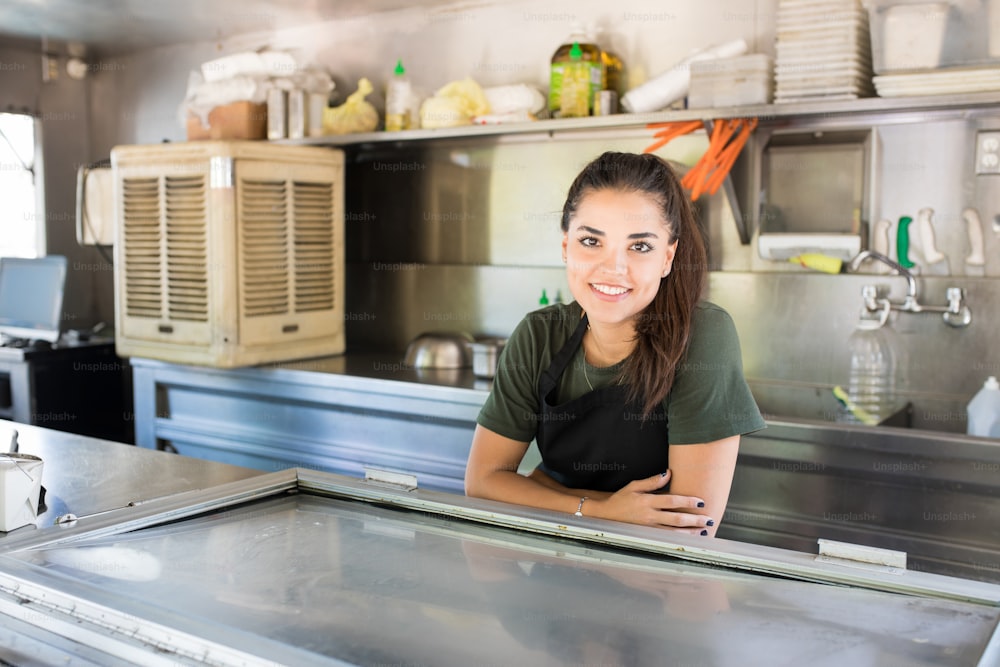 Cute young brunette working on a food truck and enjoying her job