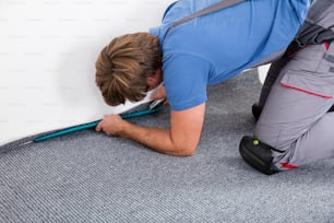 Rear View Of A Craftsman Fitting Carpet On Floor