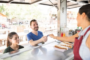 Handsome young man paying for his food with a credit card in a food truck