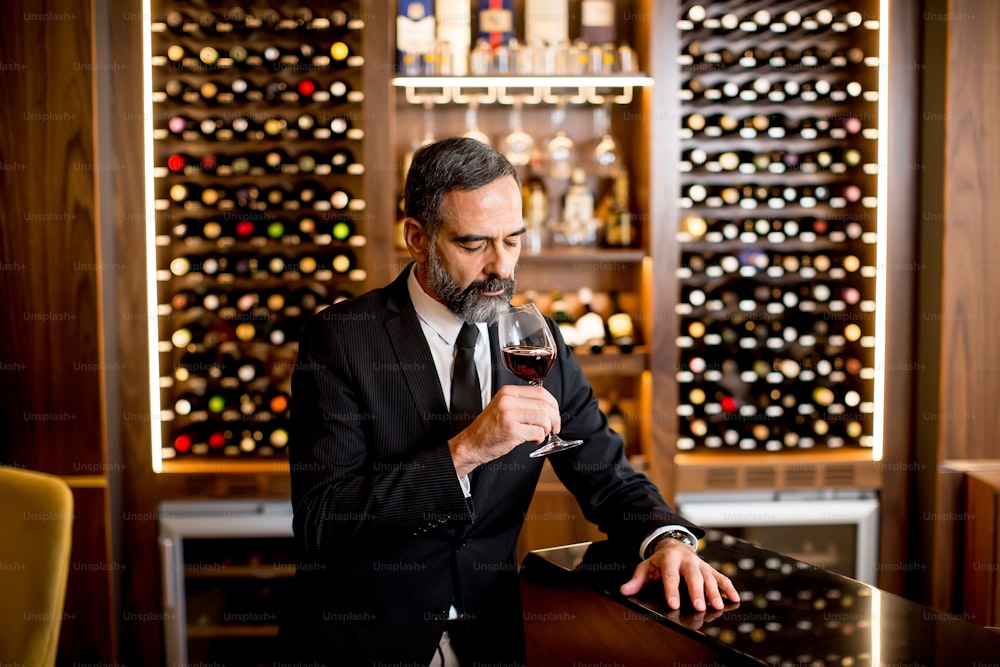 Handsome elegant businessman drinking red wine in bar