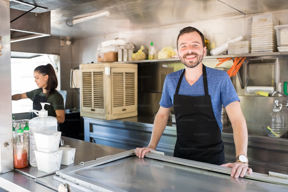 Portrait of a handsome man working inside a food truck and smiling