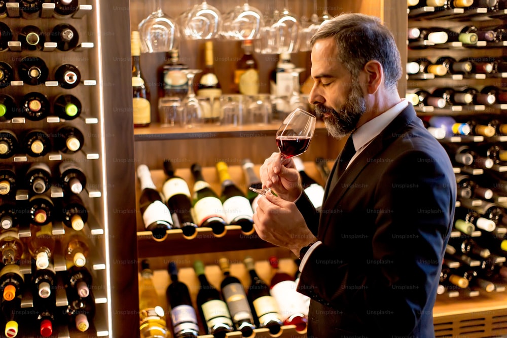 Handsome mature man tasting glass of red wine