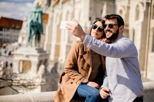 Portrait of loving couple taking selfie in urban enviroment at sunny day