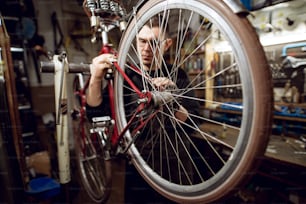 Professional young man cleaning bicycle rear bar in the workshop.