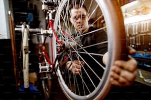 自転車の車輪のワイヤーをしっかりと調整するプロの若い男。