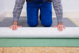 Gros plan de la main d’un travailleur installant un tapis