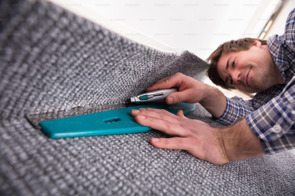 Male Carpet Fitter Installing Carpet With Cutter