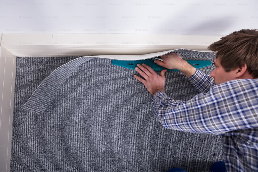 Male Carpet Fitter Installing Carpet With Cutter