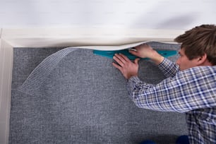 Male Carpet Fitter Installing Carpet With Cutter