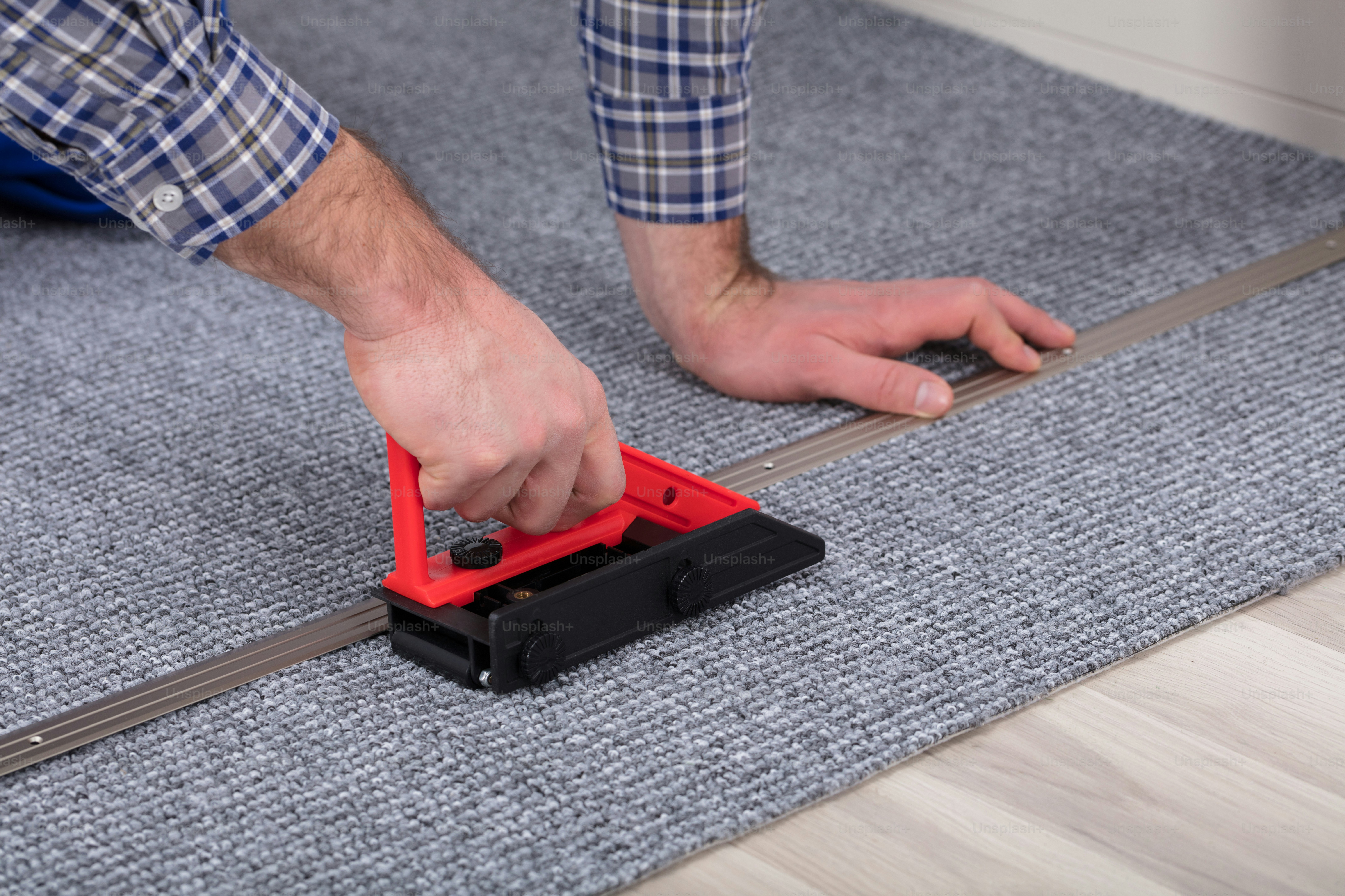 Nahaufnahme des Handanpassers eines männlichen Teppichs, der Teppich mit Werkzeug installiert