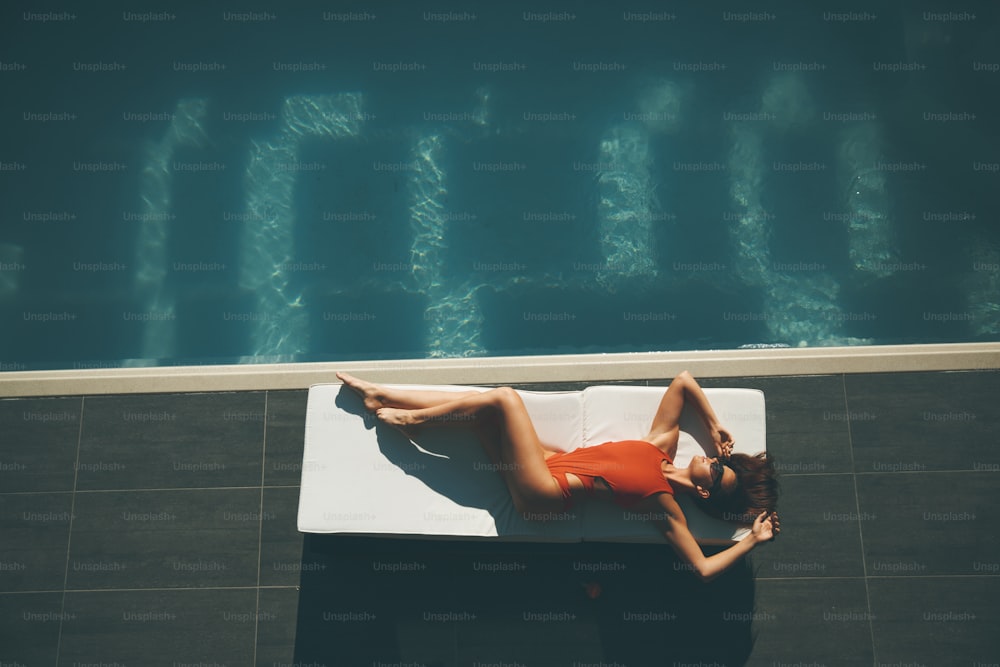 Mulher nova deitada na piscina no dia quente de verão