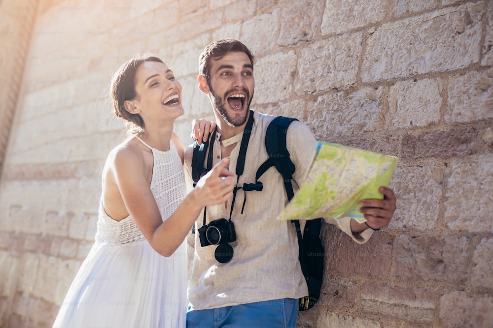 Smiling couple of tourists in sunglasses with map in the city - summer holidays, dating and tourism concept