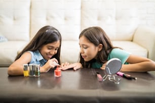 Dos hermanas jugando en la habitación pintando uñas con esmalte