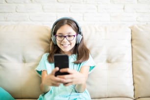 Trendy cute girl relaxing at home listening to music in headphones