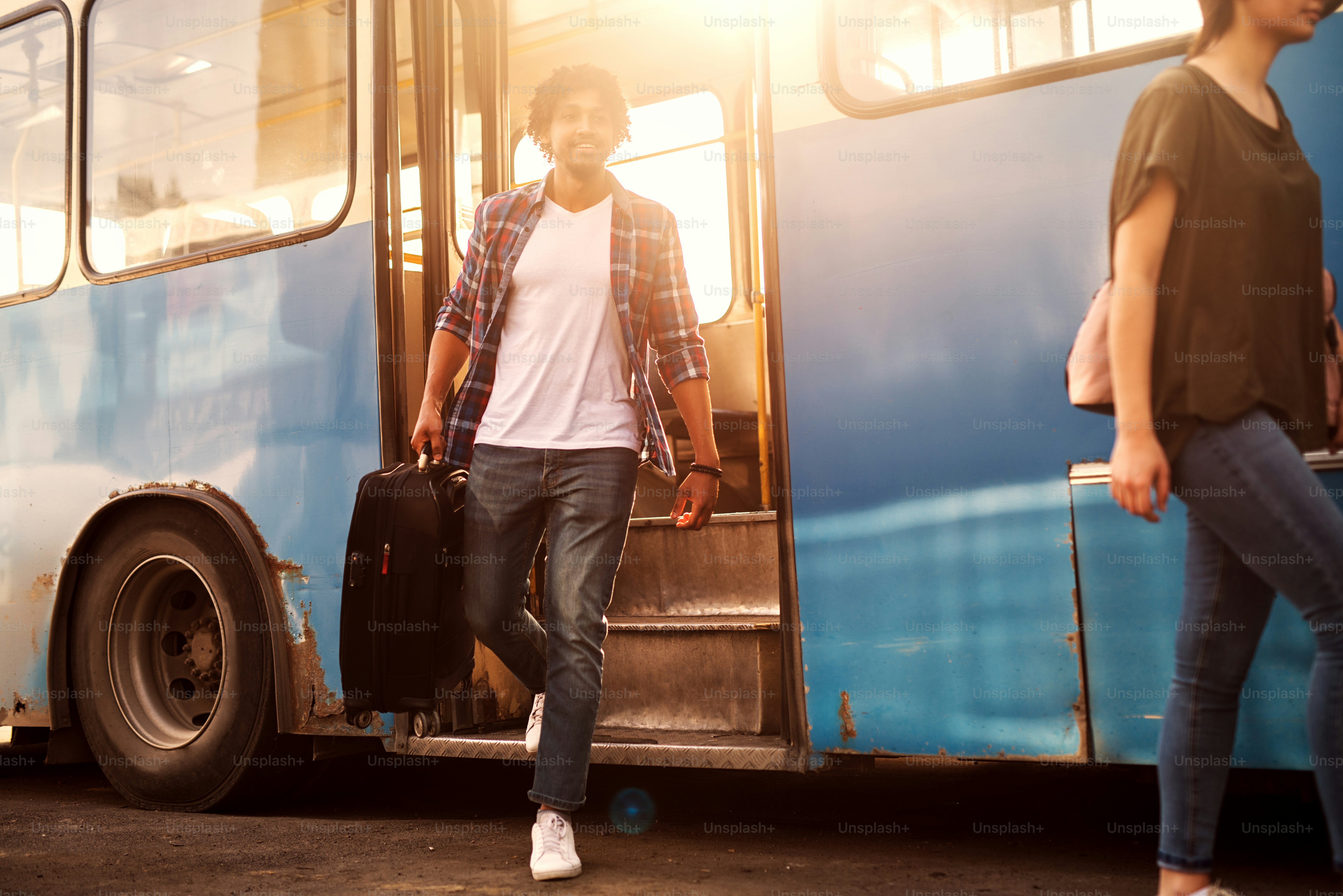 Der junge, gutaussehende Mann verlässt den Bus mit seiner Reisetasche.