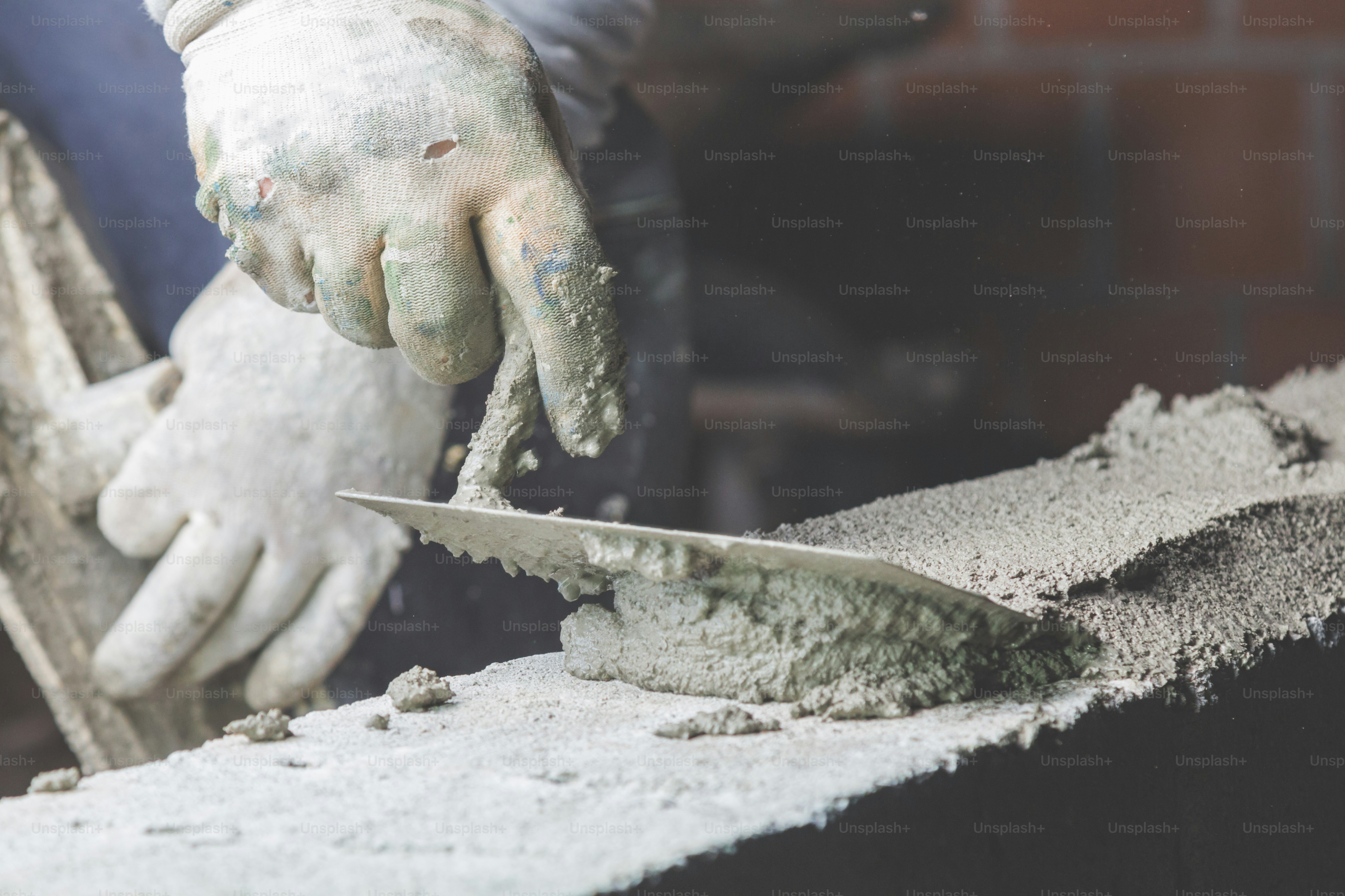 Real construction worker bricklaying the wall using tools.