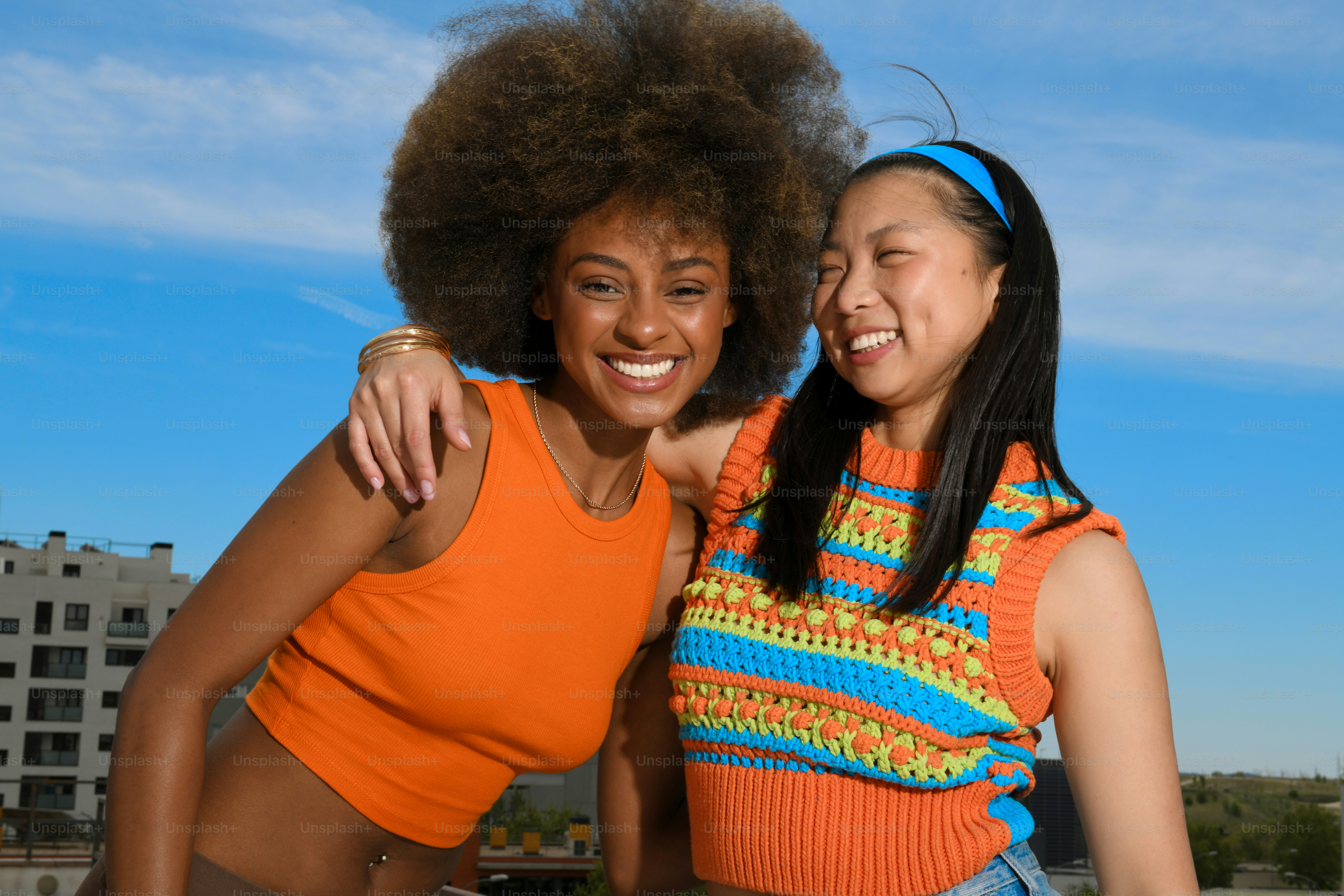 two women standing next to each other in front of a blue sky