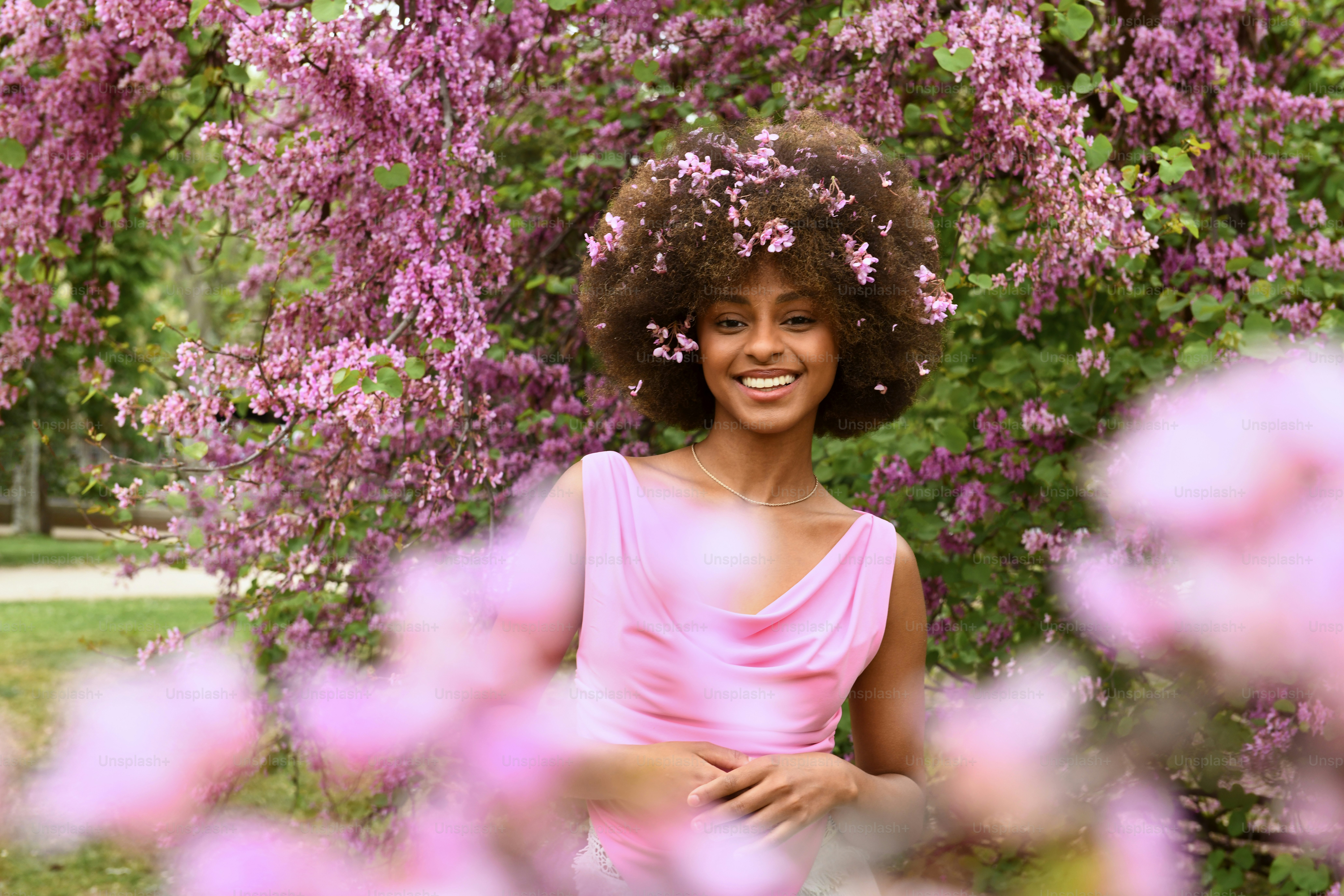 a woman standing in front of purple flowers