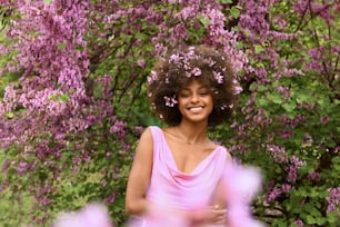 a woman in a pink dress standing in front of purple flowers
