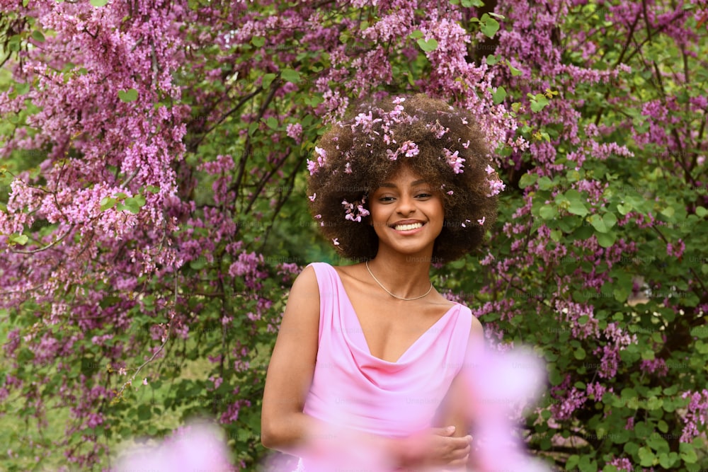 a woman in a pink dress standing in front of purple flowers