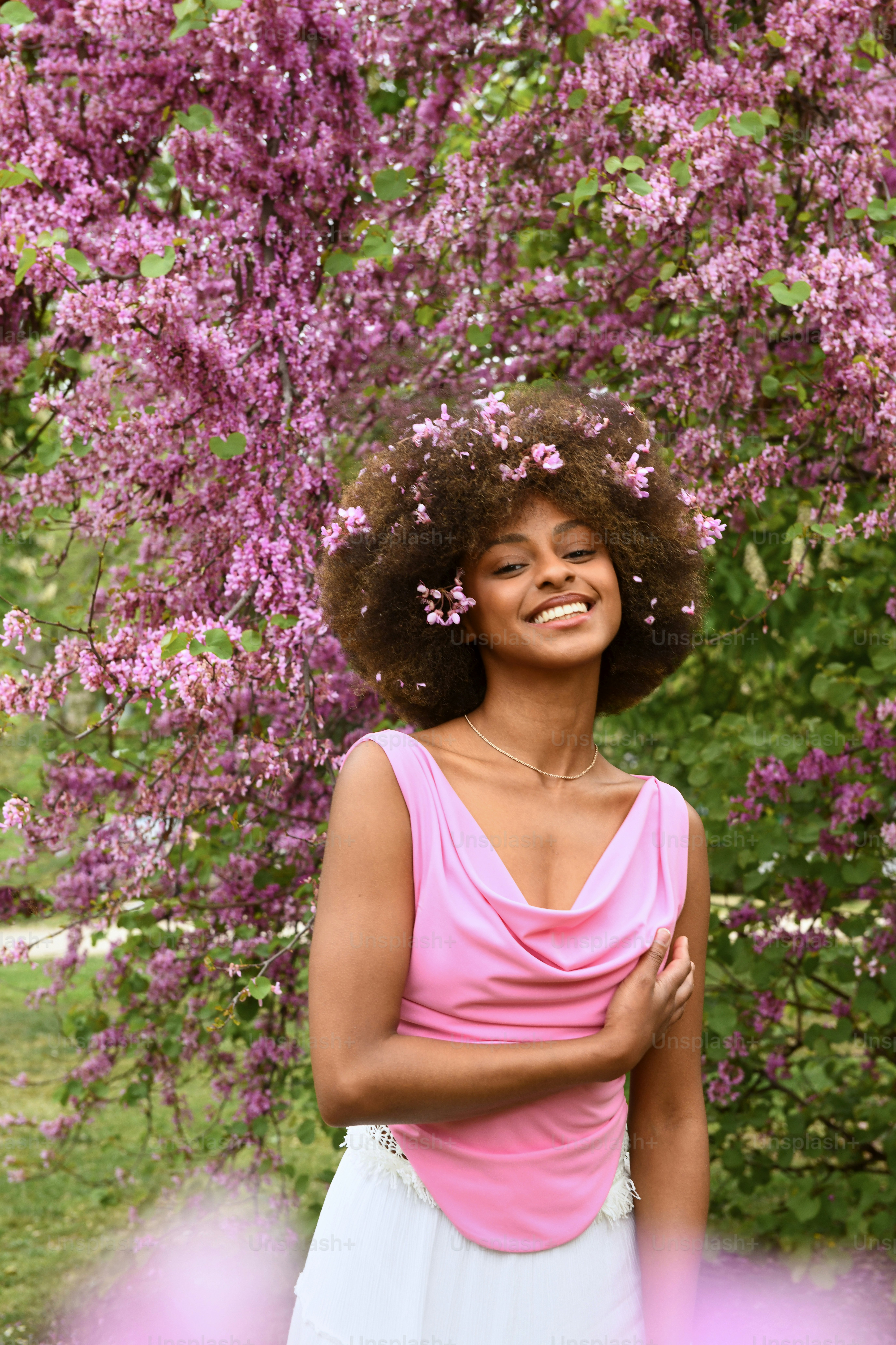 紫色の花を持つ木の前に立つ女性