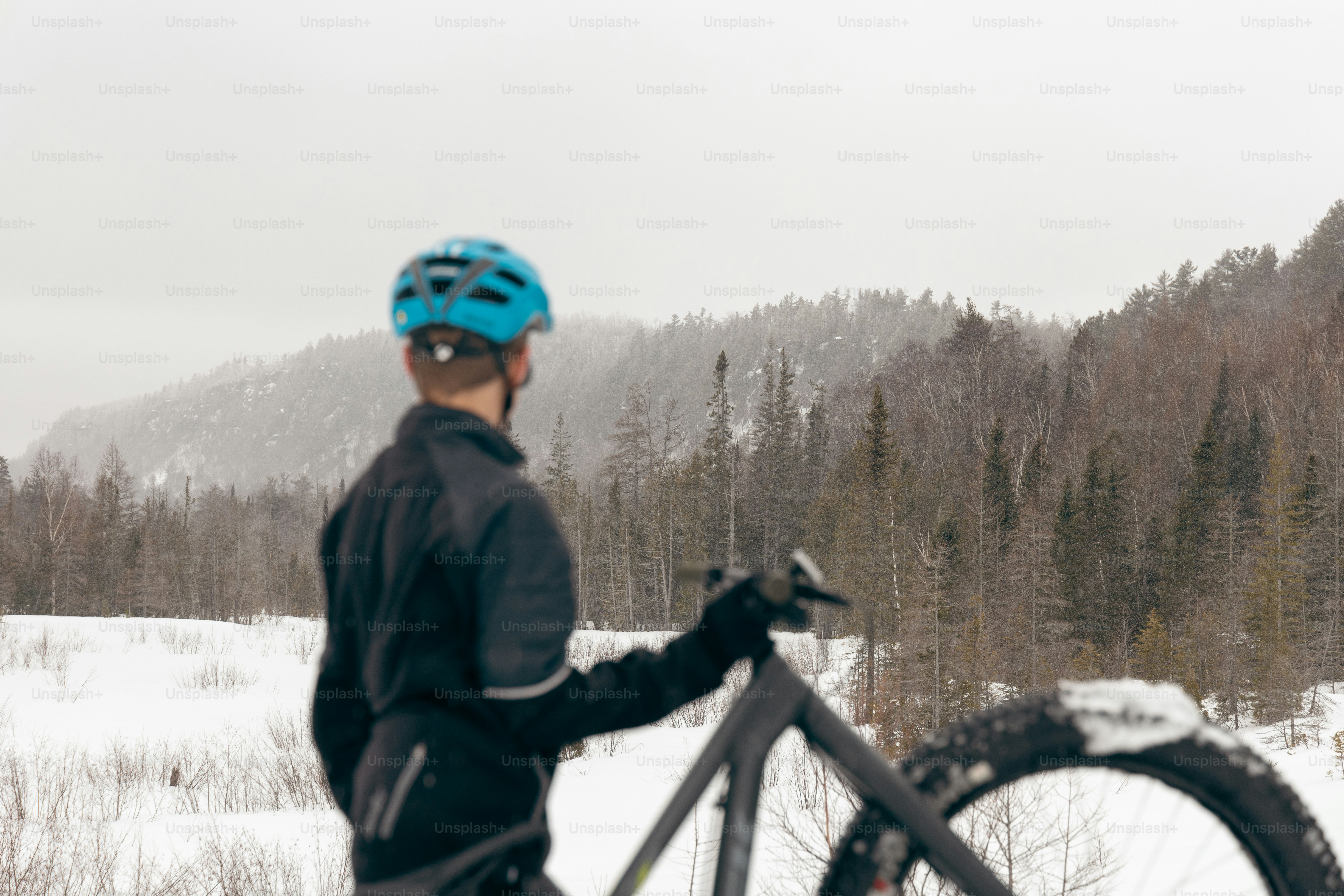 a man standing next to a bike in the snow